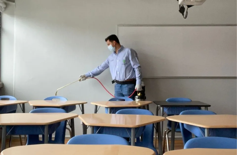 Técnico de SEPROFU desinfectando y fumigando salón de clases