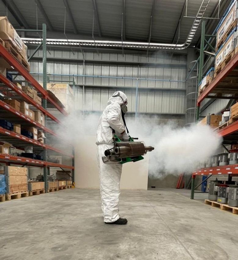 Técnico de SEPROFU fumigando y desinfectando un almacén con un equipo especializado.