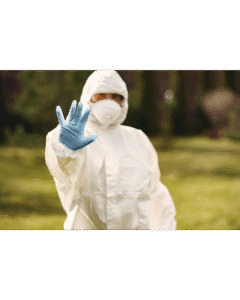 Técnico de control de plagas con traje de protección señalando una zona de riesgo sobre fondo amarillo.