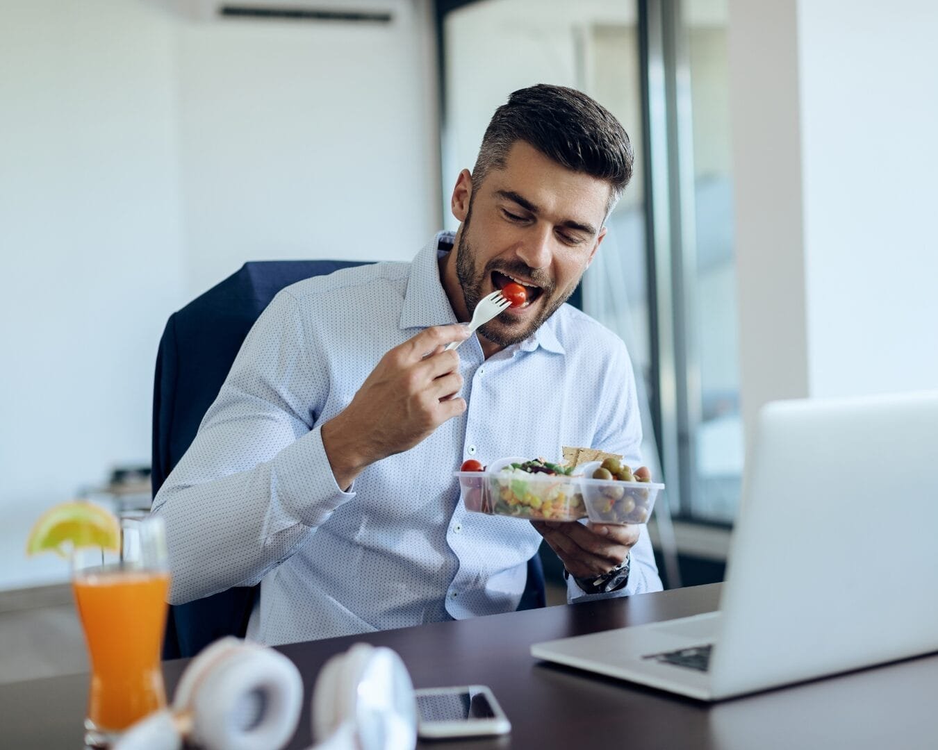 Empleado comiendo alimentos en su escritorio dentro de una oficina, posible foco de atracción de plagas.