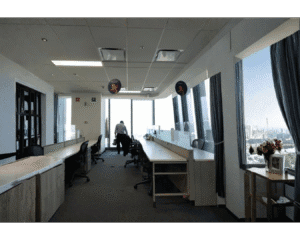 Oficina vacía con escritorios alineados y vista a la ciudad, posible riesgo de plagas al cerrar por vacaciones.