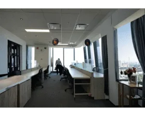 Oficina vacía con escritorios alineados y vista a la ciudad, posible riesgo de plagas al cerrar por vacaciones.