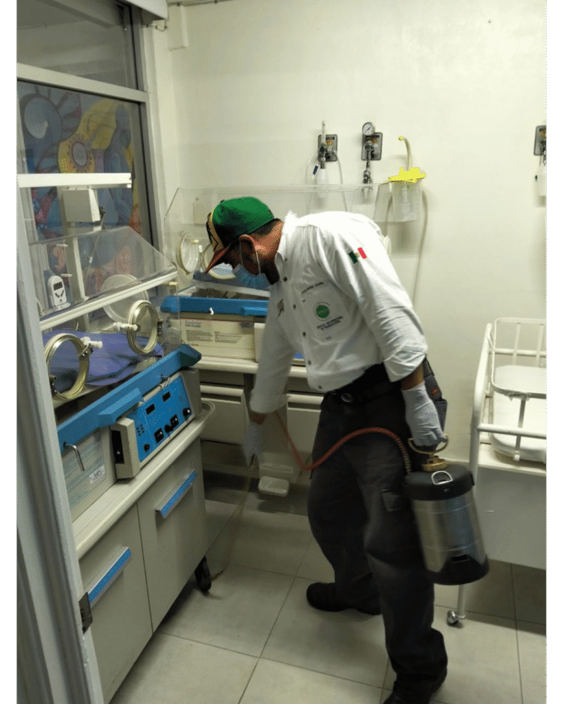 Técnico de SEPROFU realizando fumigación profesional en área médica con incubadoras, como parte de acciones preventivas en salud.