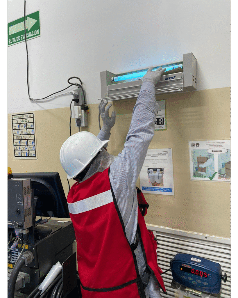 Técnico de SEPROFU instalando lámpara de luz UV para control de insectos voladores en área industrial, como parte de acciones preventivas de higiene ambiental.