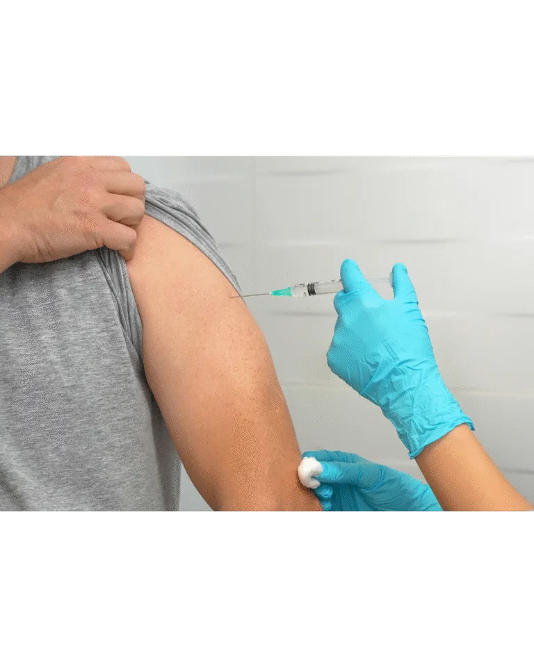 Persona recibiendo una vacuna en el brazo, administrada por personal médico con guantes, como parte de las acciones preventivas contra enfermedades contagiosas como el sarampión.