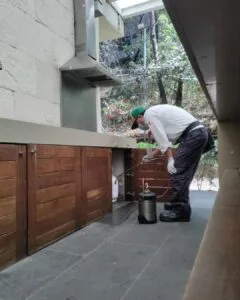 Técnico de SEPROFU aplicando control profesional de plagas en área de cocina industrial como parte de protocolos de higiene y prevención sanitaria.